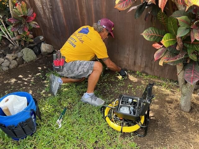 Inspector using sewer camera equipment beside an outdoor access point.