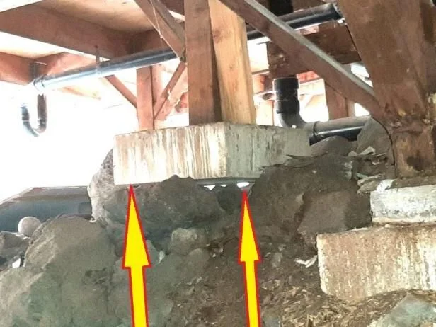 Arrows highlight gaps beneath a concrete pier supporting wooden floor framing.